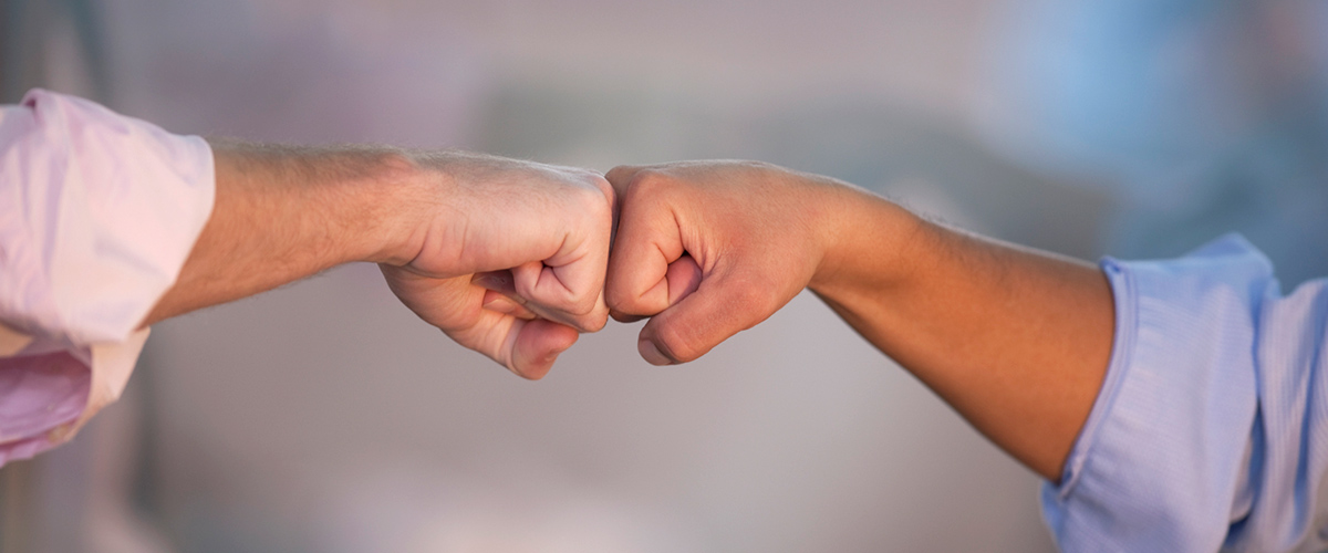 two executives connecting with a fist bump, arms and fists are only visible, demonstrate good body language