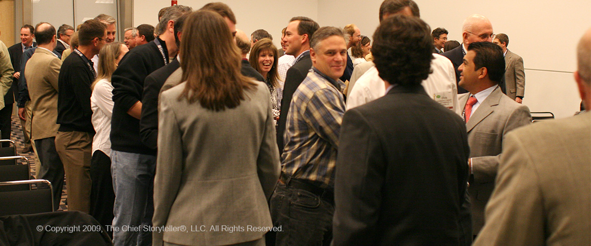 room full of executives networking, shaking hands, talking, sharing his or her elevator pitch