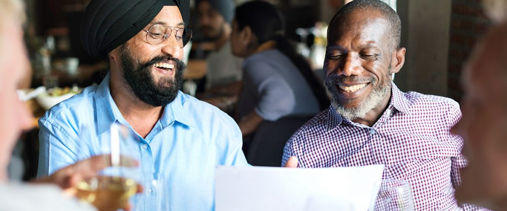 take your client to lunch, with two executives sitting in a restaurant booth, smiling broadly while looking at a piece of paper