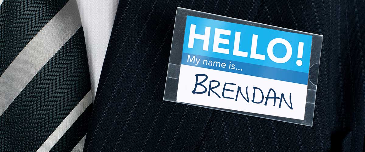 executive at networking event, wearing suit and tie, with the Brendan hand written on the name tag