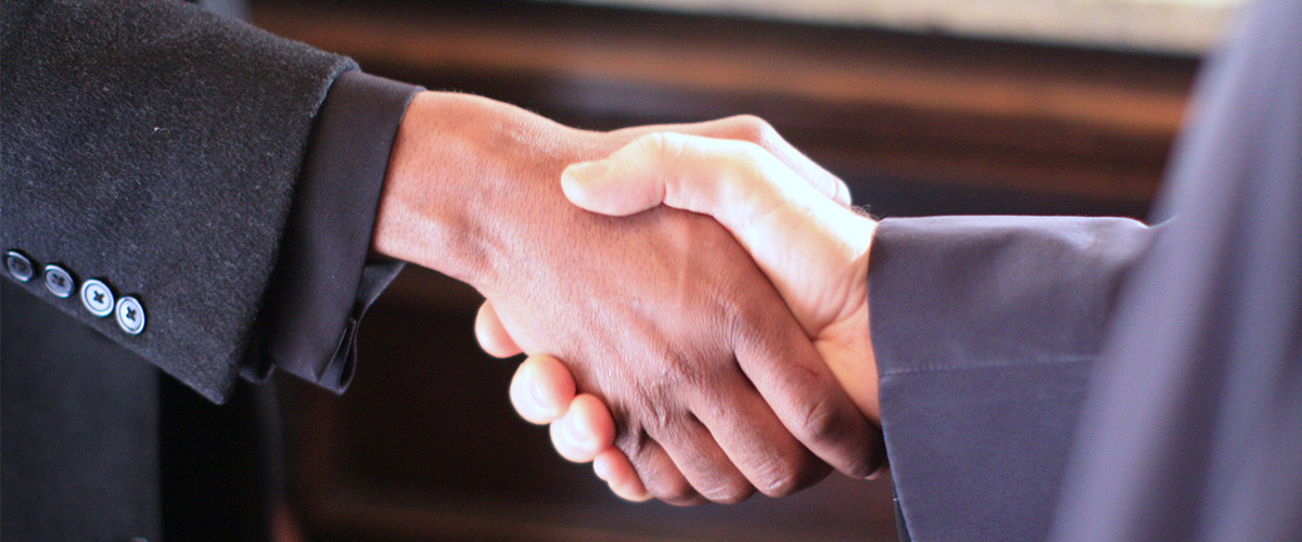 two male executive shaking hands - handshake should never be noticeable