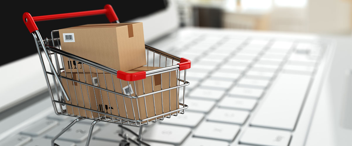miniature shopping cart with packages on top of a laptop keyboard for email marketing strategy