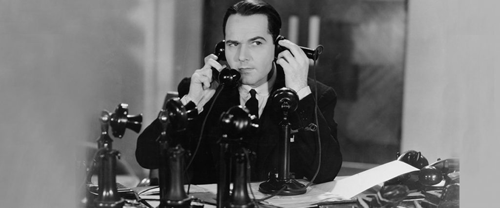 old photograph, black and white, man on two telephones
