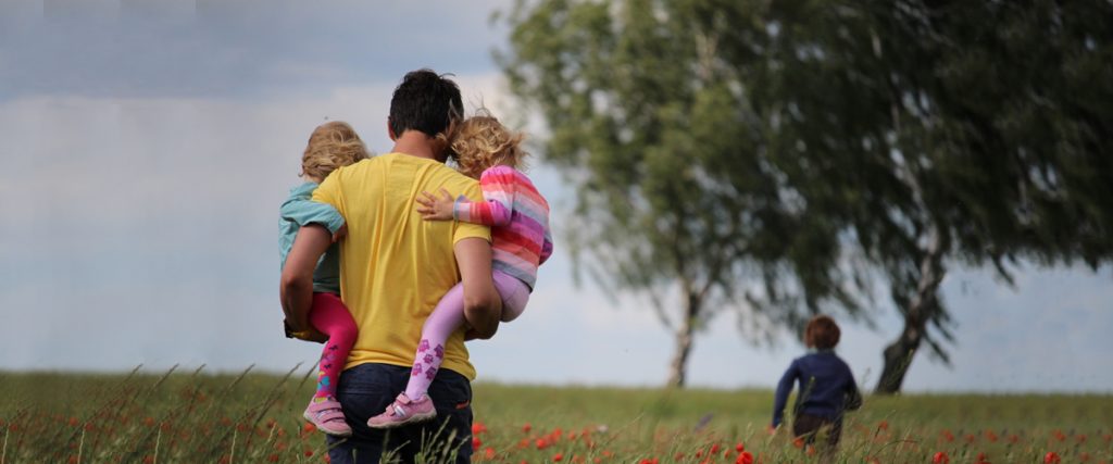 happy father's day photo with a dad and his three daughters walking in a field