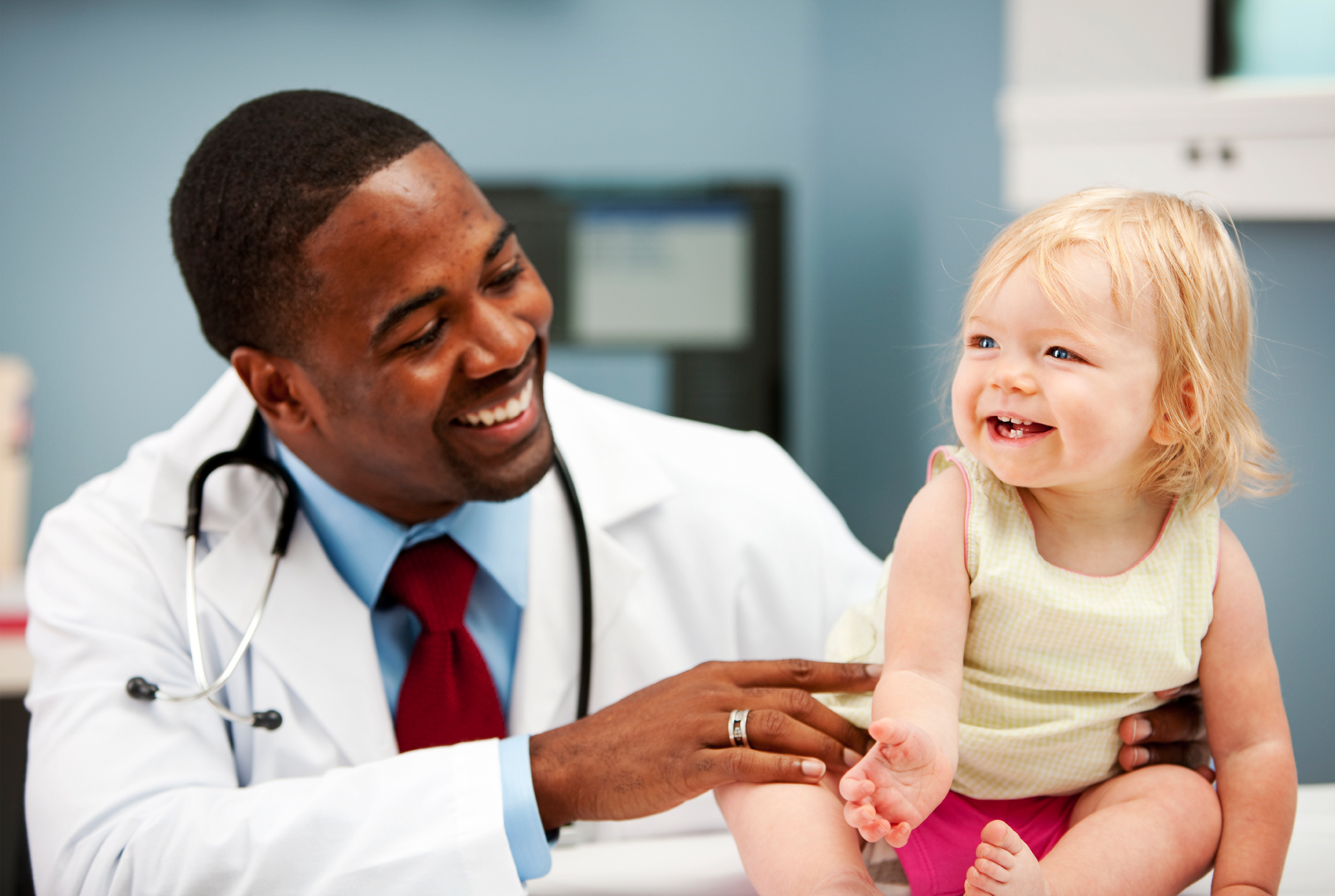 success story - male doctor examining female toddler, both smiling
