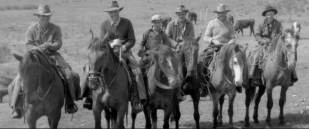 black and white, 6 cowboy ranch herders all on horseback, smiling at the camera, all supposed to work together like good consultants, like the consultants at EDS