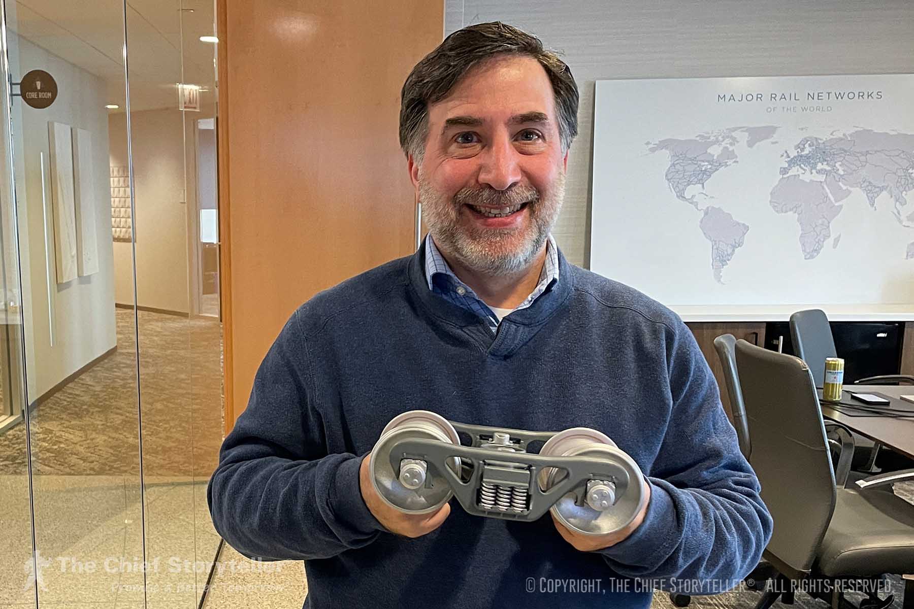 Ira Koretsky, CEO of The Chief Storyteller, holding a miniature wheel assembly for a railroad car - example of a symbol