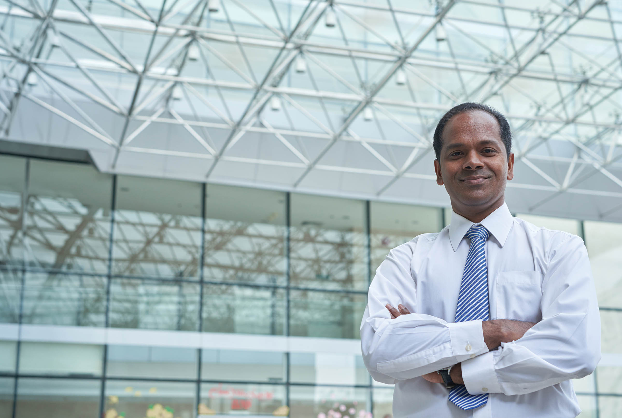 seasoned executive, CXO at a Fortune 500 company, white shirt, blue tie, arms crossed with a confident smile